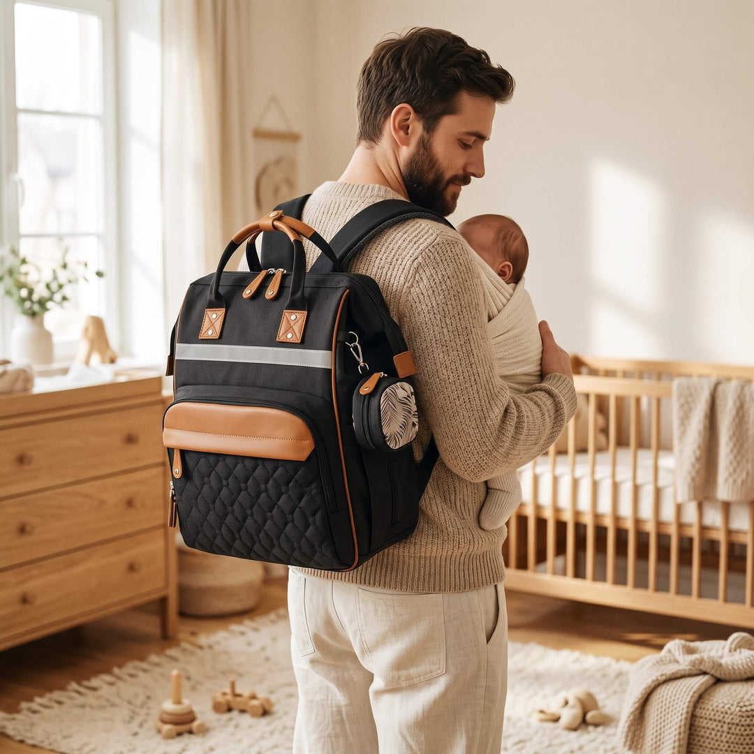 Sac à langer à dos porté par un jeune papa avec son bébé en porte-bébé, intérieur scandinave en bois clair