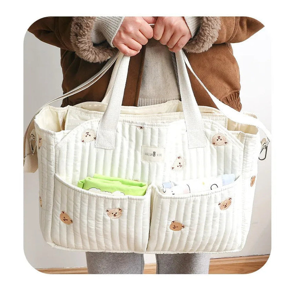 Sac à langer besace matelassé Maison Lunö porté à la main, poches en façade garnies