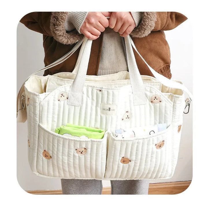 Sac à langer besace matelassé Maison Lunö porté à la main, poches en façade garnies